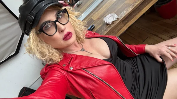 Lucy Hart in a red leather jacket and a tight, low cut dress